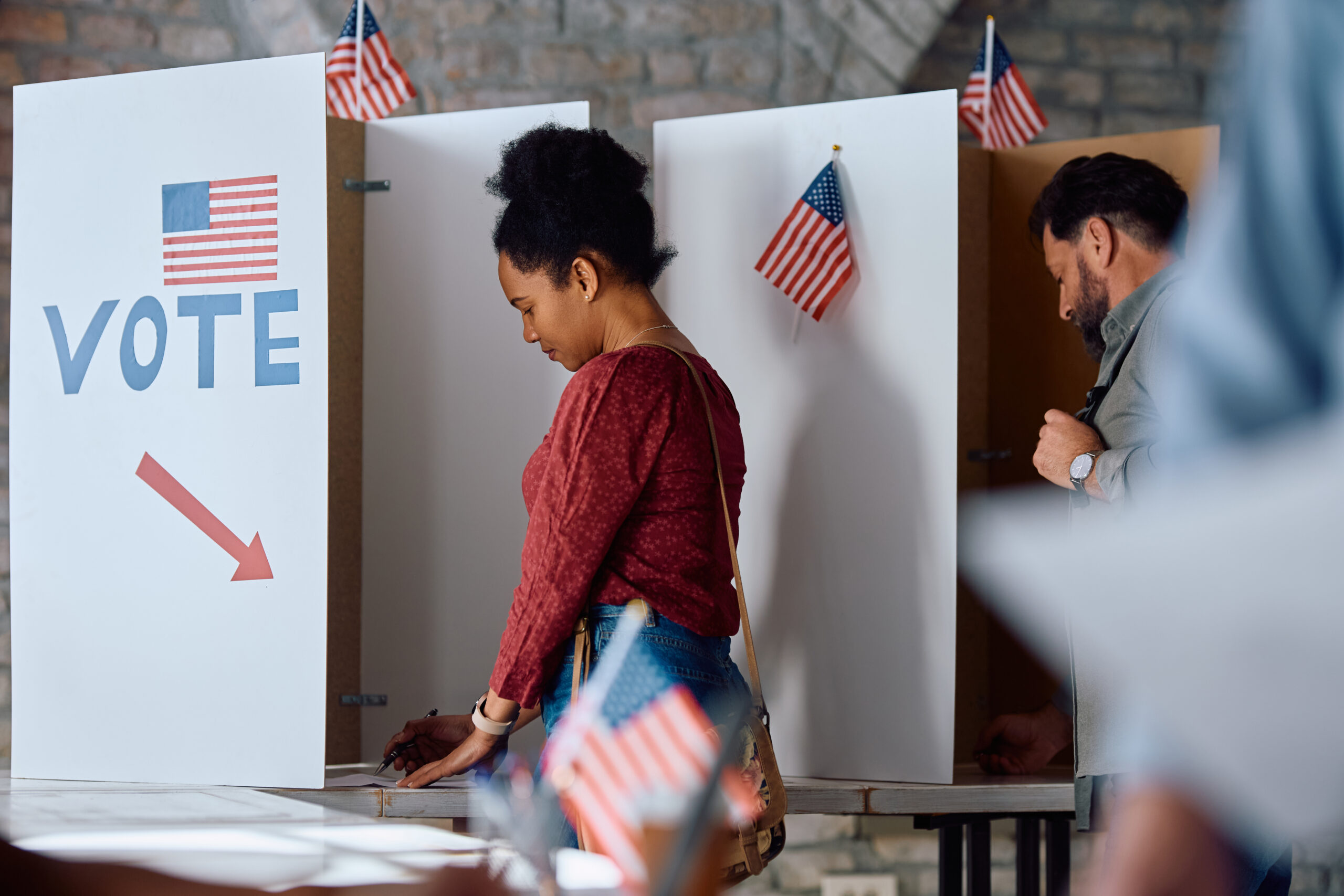 Black female citizen voting at polling station during elections in USA by drazenphoto